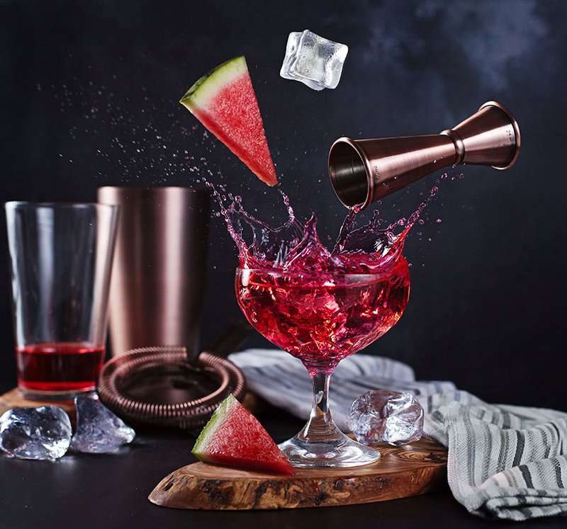 Roter Cocktail spritzt in Glas, mit schwebender Wassermelone, Messbech Roter Cocktail spritzt in Glas, mit schwebender Wassermelone, Messbech