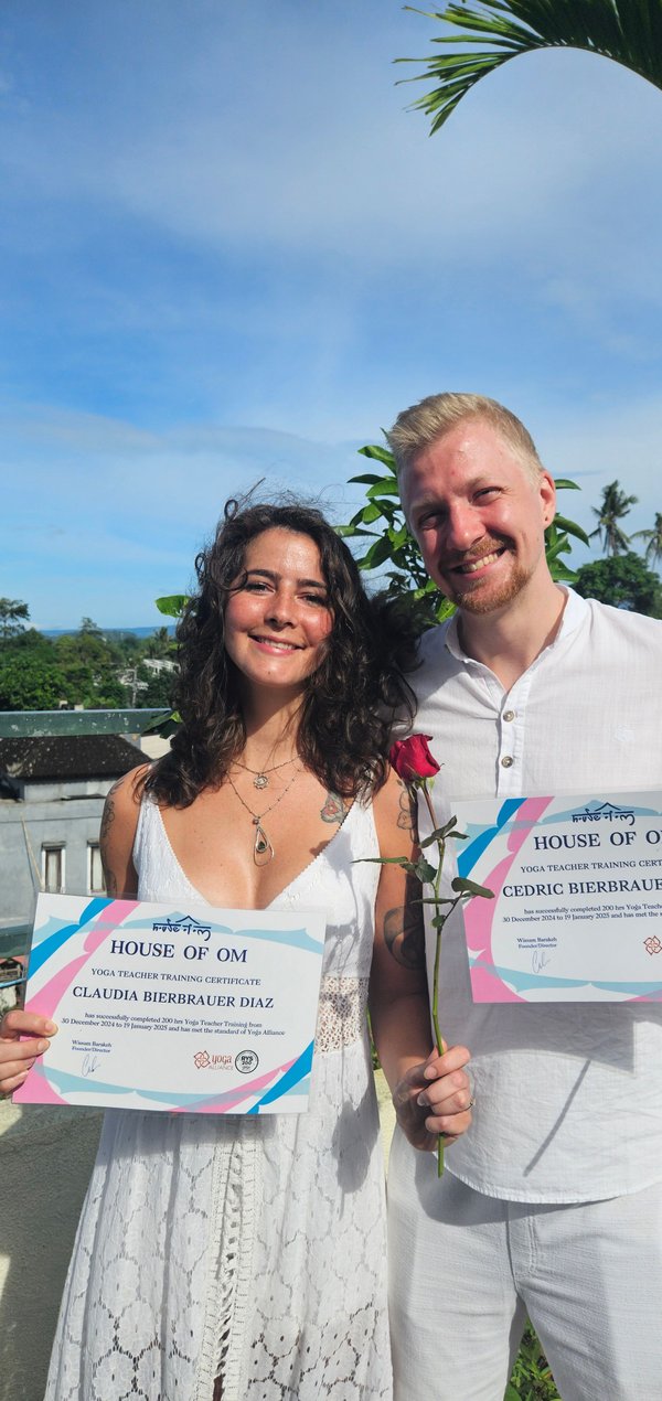 Cedric und Claudia Bierbrauer Diaz halten lächelnd ihr Yogalehrer-Zertifikat über 200 Stunden Yoga Teacher Training. Cedric und Claudia Bierbrauer Diaz halten lächelnd ihr Yogalehrer-Zertifikat über 200 Stunden Yoga Teacher Training.