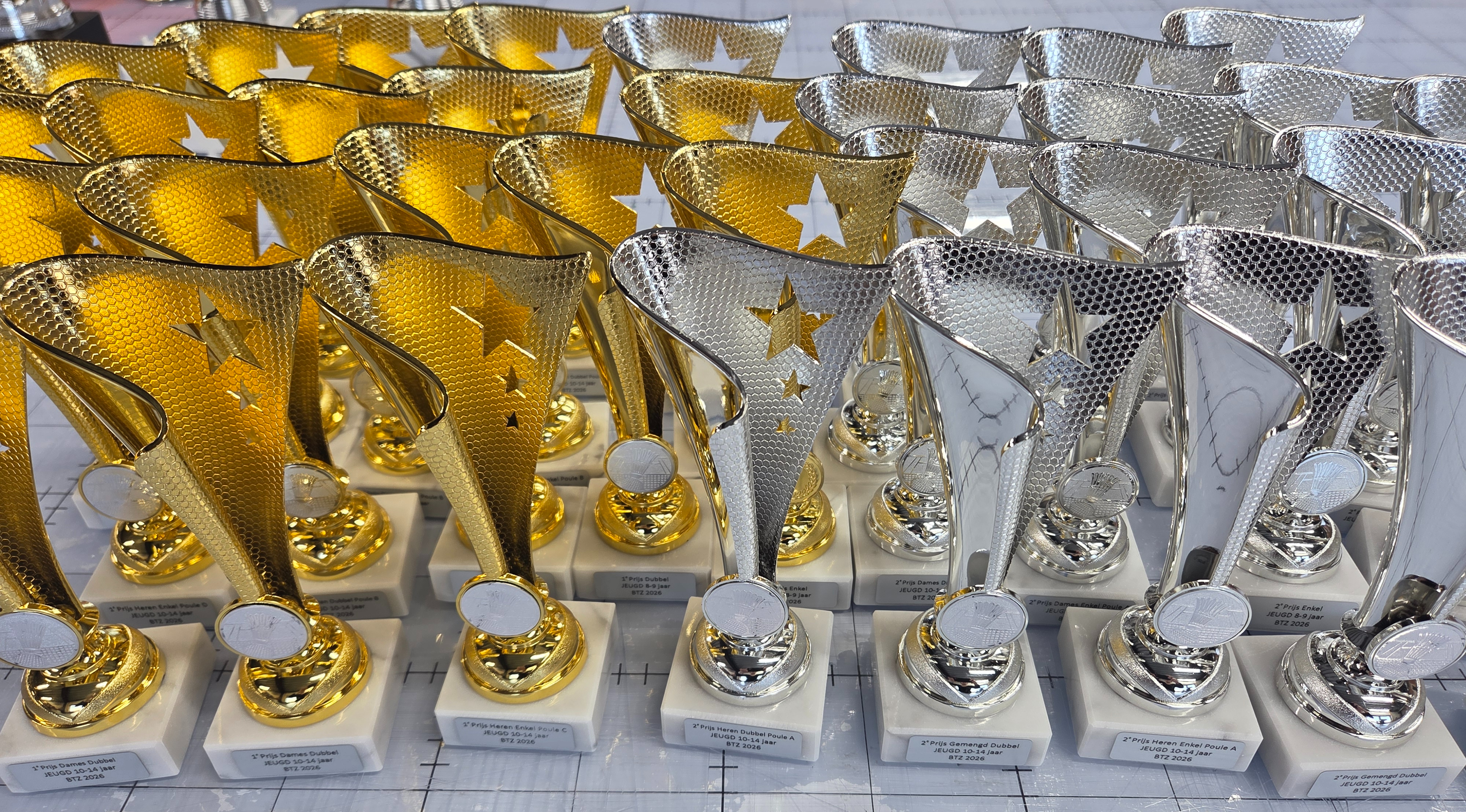 Rijen gouden en zilveren sportbekers op marmeren voet