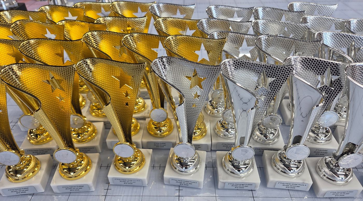 Rijen gouden en zilveren sportbekers op marmeren voet