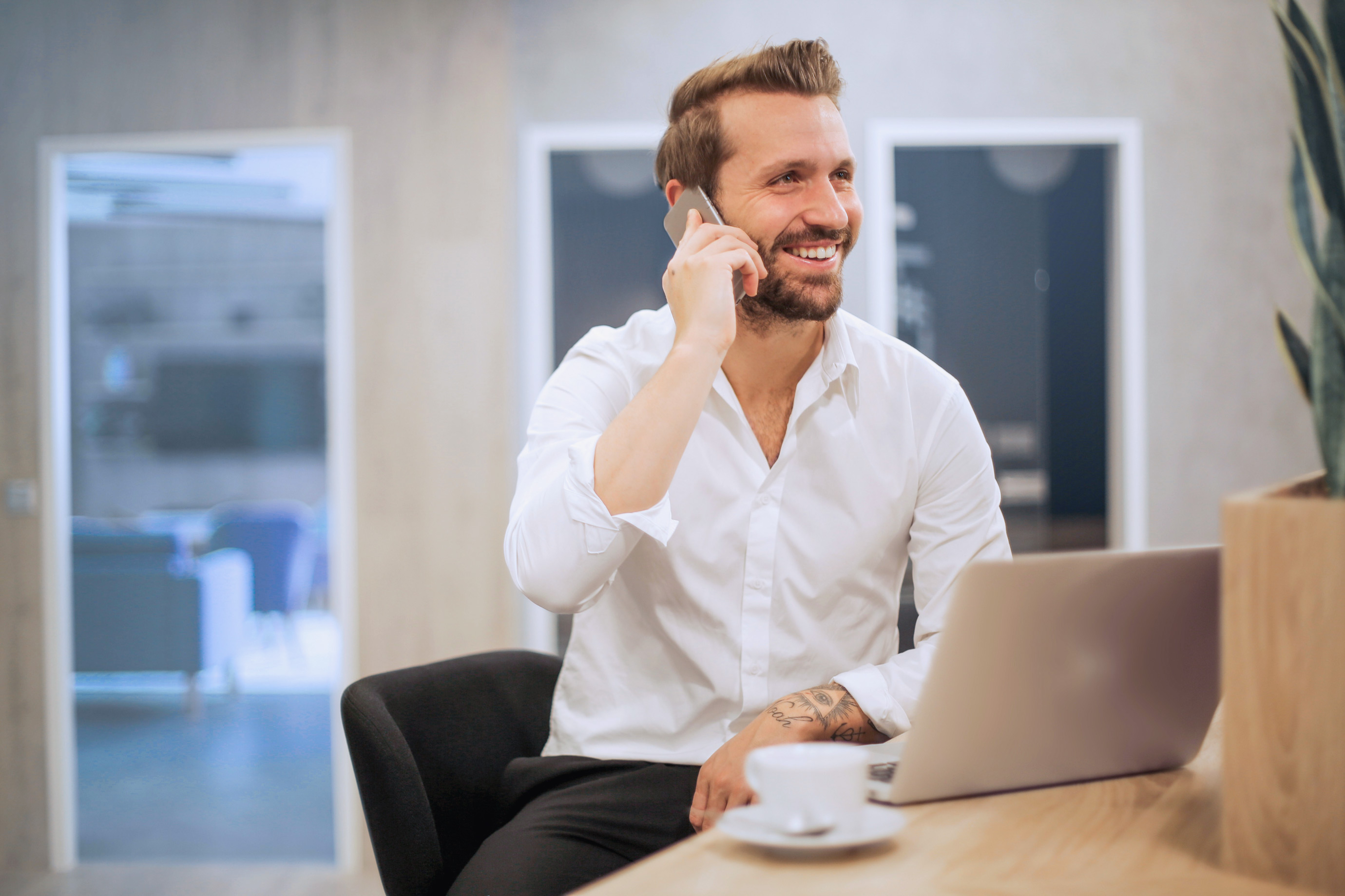 En glad affärsman som pratar i telefon med en kund på kontoret