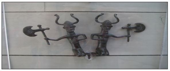 To bronsefigurer som viser et par knelende menn med bronseøkser og hjelmer med horn som gjør tegn med armene sine.  De har nok opprinnelig hørt til en større prosesjonsgruppe i sin samtid. Fra: Vitlycke museum, Tanum, Sverige. Foto: Heine Iversen.