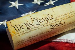 A picture of the U.S. Constitution on top of a U.S. Flag