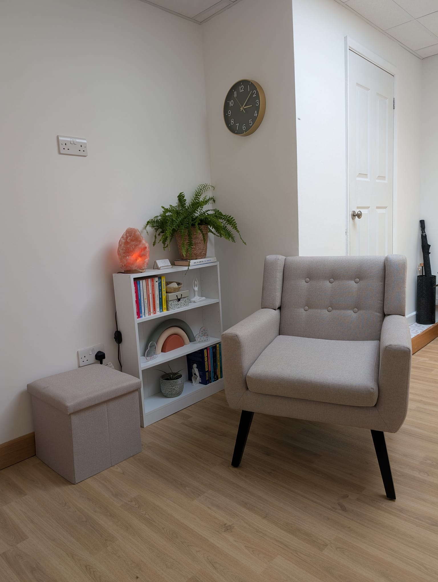 Photograph of a grey chair with a green cushion and green blanket overhanging the arm of the chair.