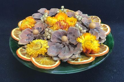 Herfststukje in glazen schaal met droogbloemen, appelsien, ...