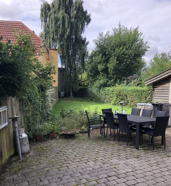 Hyggelig have med terrasse, skur og græsplæne.