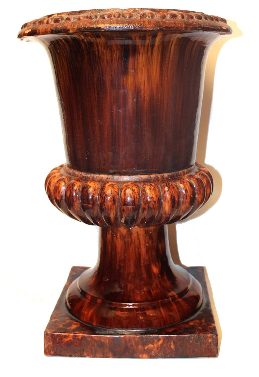 Urne de jardin Dion. Terre cuite rouge,  glaçure marbrée au manganèse avec stries verticales,  de type Rockingham. Fleurs de lys au pourtour de la partie supérieure et bourrelets à la ceinture. C. 1875-1910. Hauteur 58 cm.