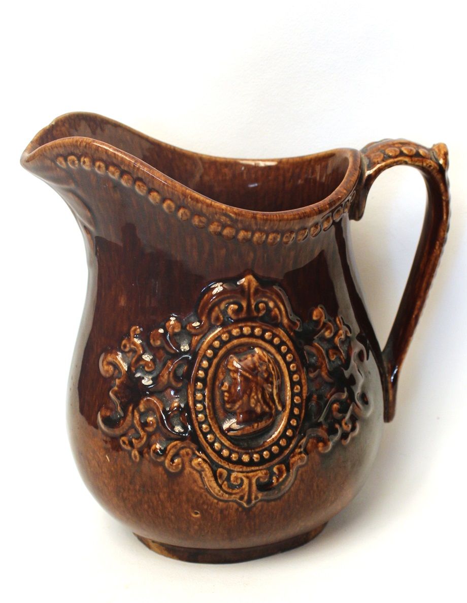Pichet en terre cuite fine jaune, à glaçure Rockingham, au motif de guerrier antique en médaillon ovale perlé entouré d'arabesques.