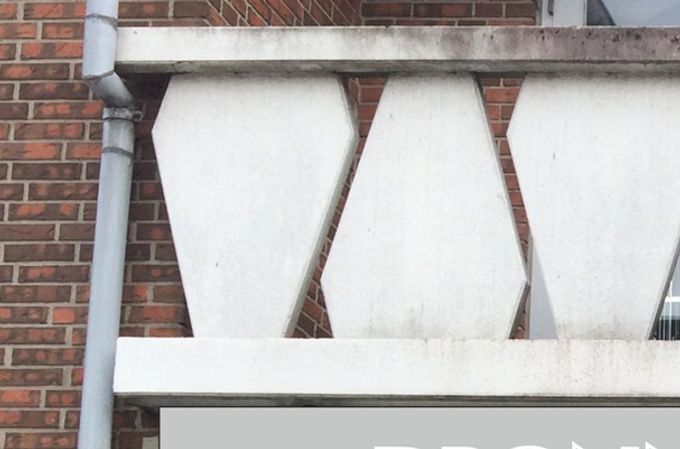 Lysskilt med sølvgrå bund, sorte bogstaver med hvid kontur. Rød logo og striber i translucent folie.