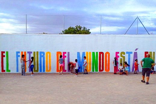 Niños y niñas pintando la frase del arte mural "Tú también pintas".