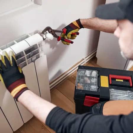 Centralvarmemekaniker og handyman reparerer radiator i hjemmet