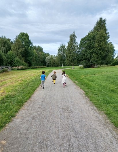 Tre barn springer på lantlig väg på utflykt med förskolan Tre barn springer på lantlig väg på utflykt med förskolan