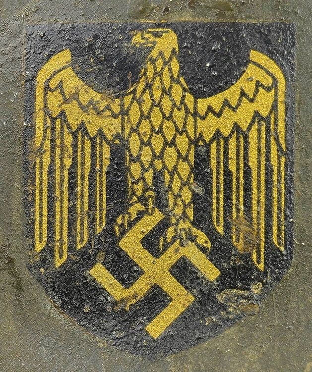 KM decal on an M40 ET. This example has more prominent lines in the eagle and is referred to by collectors as a «blacklined» decal. The gold color is also deeper than the previous Quist decal. On the upper side of the right wing you can clearly see the black border line indicating two-sheet construction. This decal was applied on both Quist and ET KM helmets.