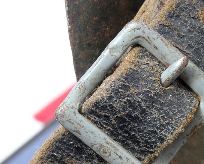 Painted steel buckle on an M40. This chinstrap is dyed black and the holes for the buckle prong are circular. 