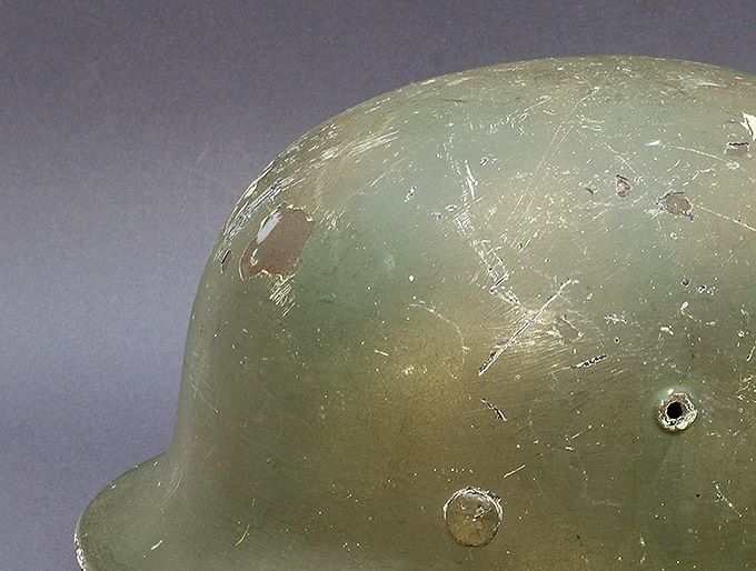 M40 ET66 hand-brushed green paint with sprayed tan paint in patterns. Underneath the camouflage paint is a layer of white winter paint.