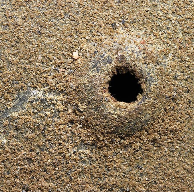 The paint structure of the M42 helmet above. The sand content of the tan paint is heavy. Notice the sand particles in the edge of the vent hole.