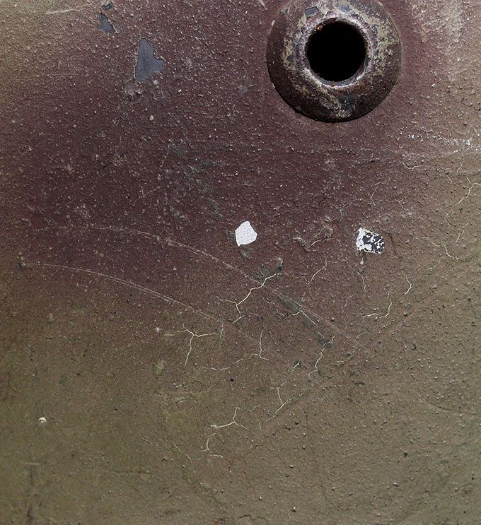 Picture showing the outline of the national shield under the paint. Some cracking has occurred in the paint. 