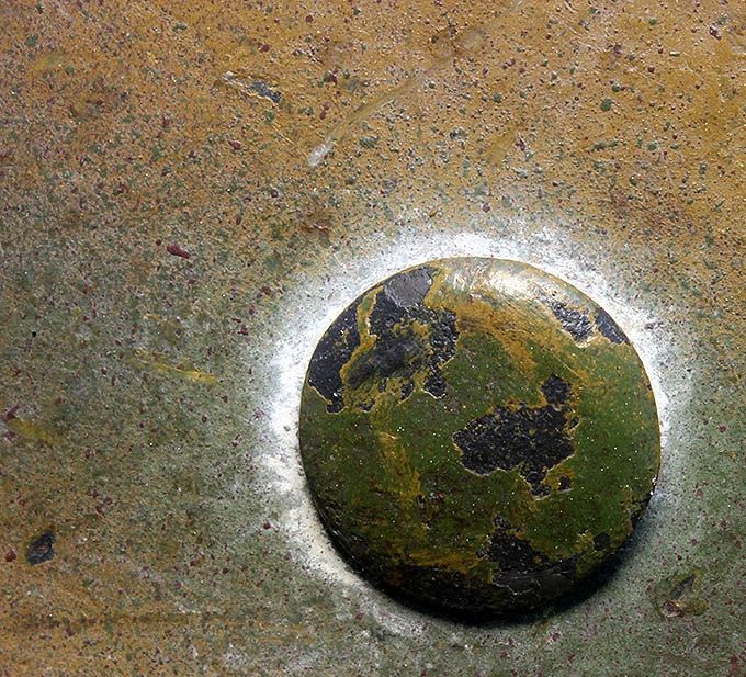 Close-up of the rivet head around which are heavy remnants of chalky whitewash.