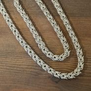 Jörgen - halsband och armband ligger lite snett på en mörk träskiva