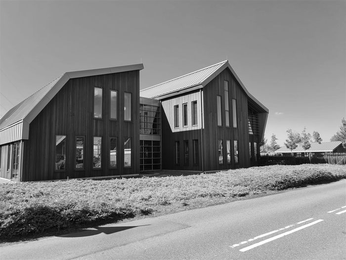 Foto 16: Foto uit 2022 
Zicht op het nieuwe kantoor van  Leegwater houtbereiding B.V. aan het Verlaat 9 en 11 in de gemeente Heerhugowaard.  Genomineerd als een van de mooiste bedrijfsgebouwen van Westfriesland door het Westfries Genootschap. Het gebouw is opgedeeld in tweeën met een glazen verbinding. Door het opdelen van de massa ontstaat een mooie ruimtewerking, waardoor het aansluit bij de schaal en de maat van de omgeving. De houten delen zijn van verschillende breedte, waardoor een rijk beeld ontstaat. Uiteindelijk werd het nieuwe Oogcentrum aan de Westerweg in Heerhugowaard Centrum gekozen als mooiste gebouw. 