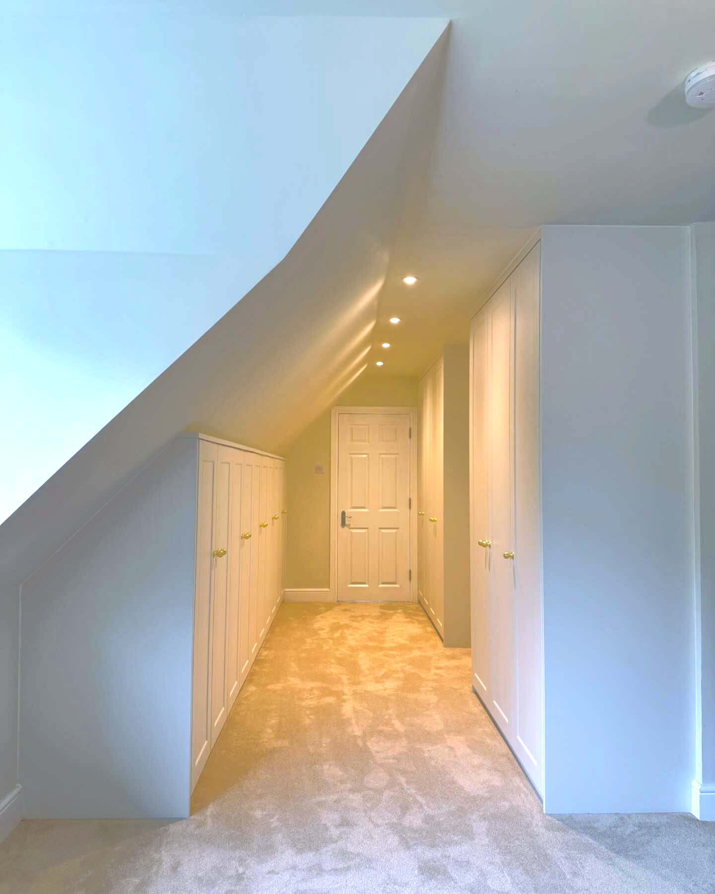 white angled wardrobe with brass nobs