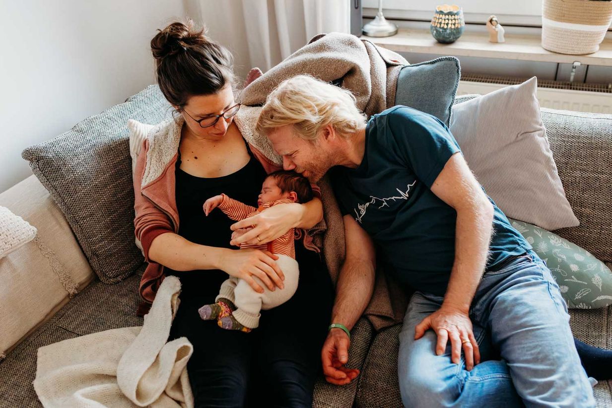Vater küsst liebevoll Neugeborenes - Homestory Babyshooting München