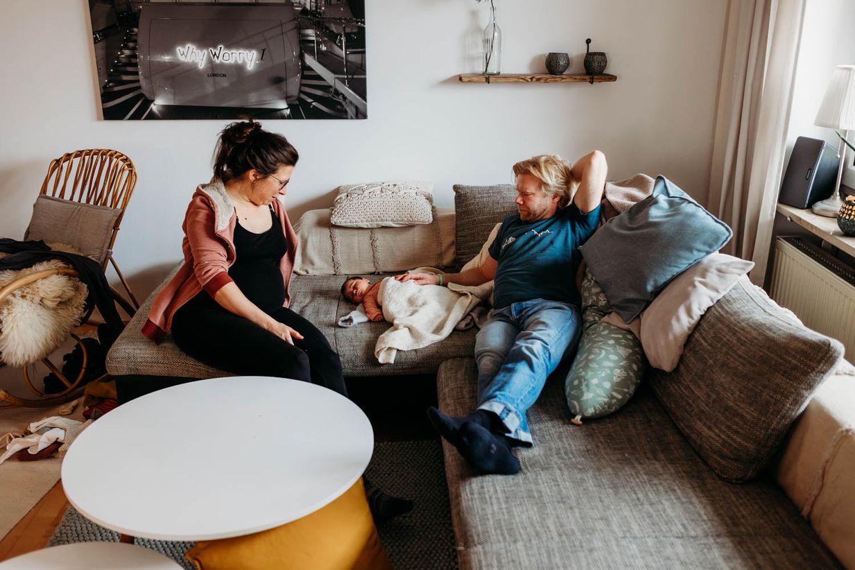 Familie mit Baby sitzt entspannt auf der Couch - ungestellte Babyfotos
