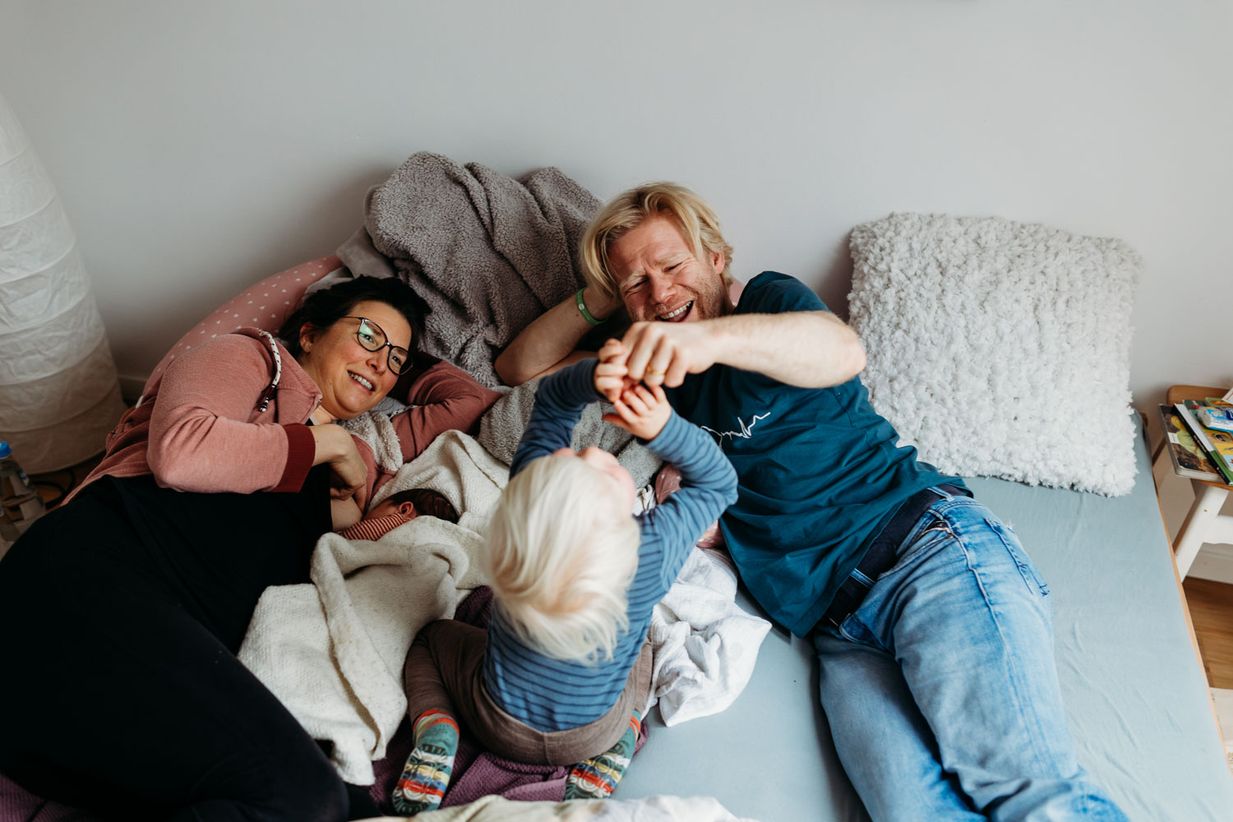 Familie kuschelt im Bett - entspannte Familienfotos München - Landshut