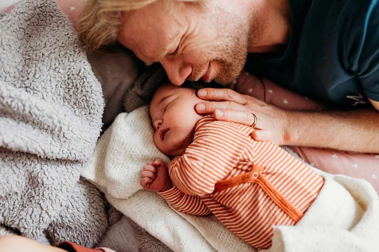 Papa kuschelt mit Neugeborenem - authentisches Babyshooting Landshut