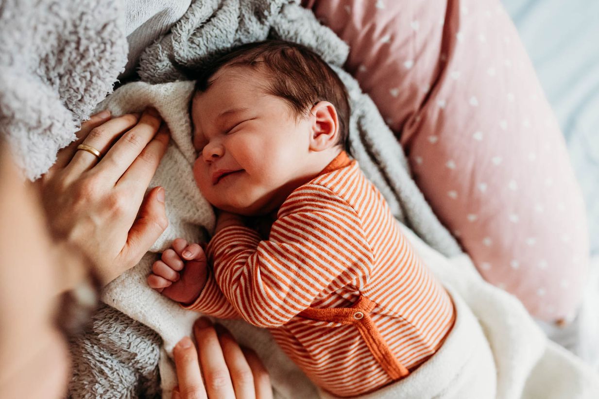 Baby lächelt im Schlaf - ungestellte Newbornfotos München - Landshut