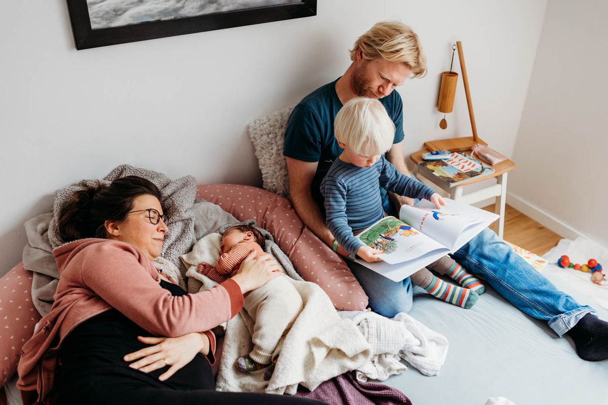 Familie liegt entspannt im Bett - echte Wochenbettfotos München