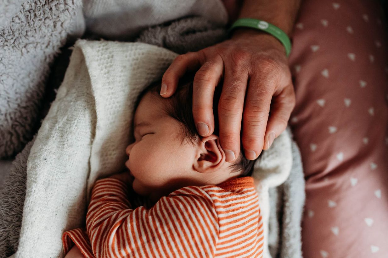 Hand des Papas ruht auf Kopf des Babys -Detailaufnahme Newborn München