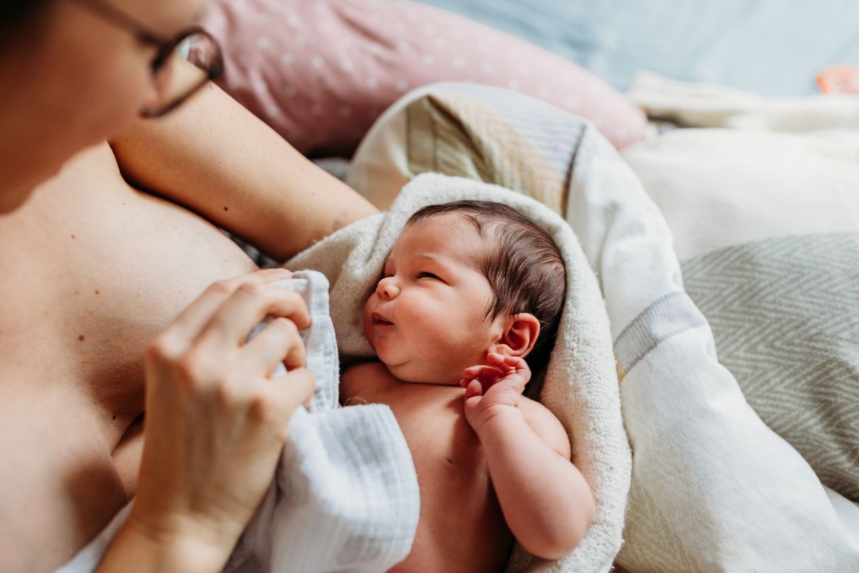 Neugeborenes liegt im Arm der Mutter - natürliche Newbornfotos München