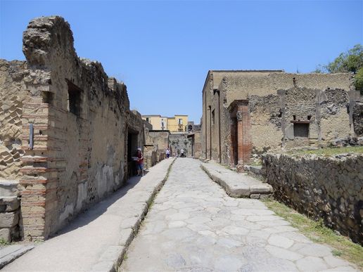Decumano inferiore seen from its intersection with Cardo V.  On the right one can see the red brick portal of the House with large Portal.  The door just opposite the portal Leads to the Taberna Vasaria.
