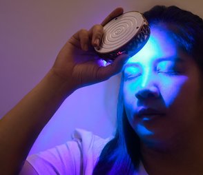 Person using 7Chakra Activator with blue light for energy balance and chakra healing.
