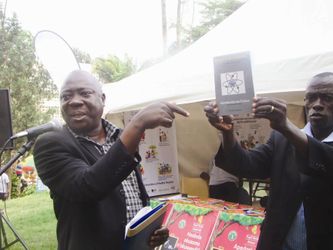 Mw. Charles Muwanga (ku kkono) ng'alaga ekitabo kya ssaayansi kye yawandiika.