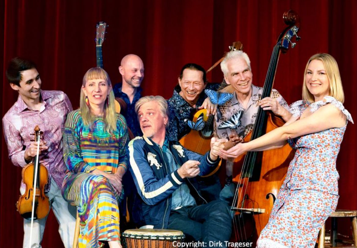 bunt gekleidete Musiker*innen mit ihren Instrumenten