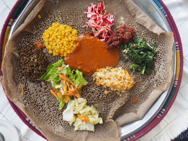 L'injera ou Injira est une galette de teff, céréale locale, au goût assez fortement acidulé et que l'on mange avec les doigts en prenant des portions des différents accompagnements, ici essentiellement des légumes