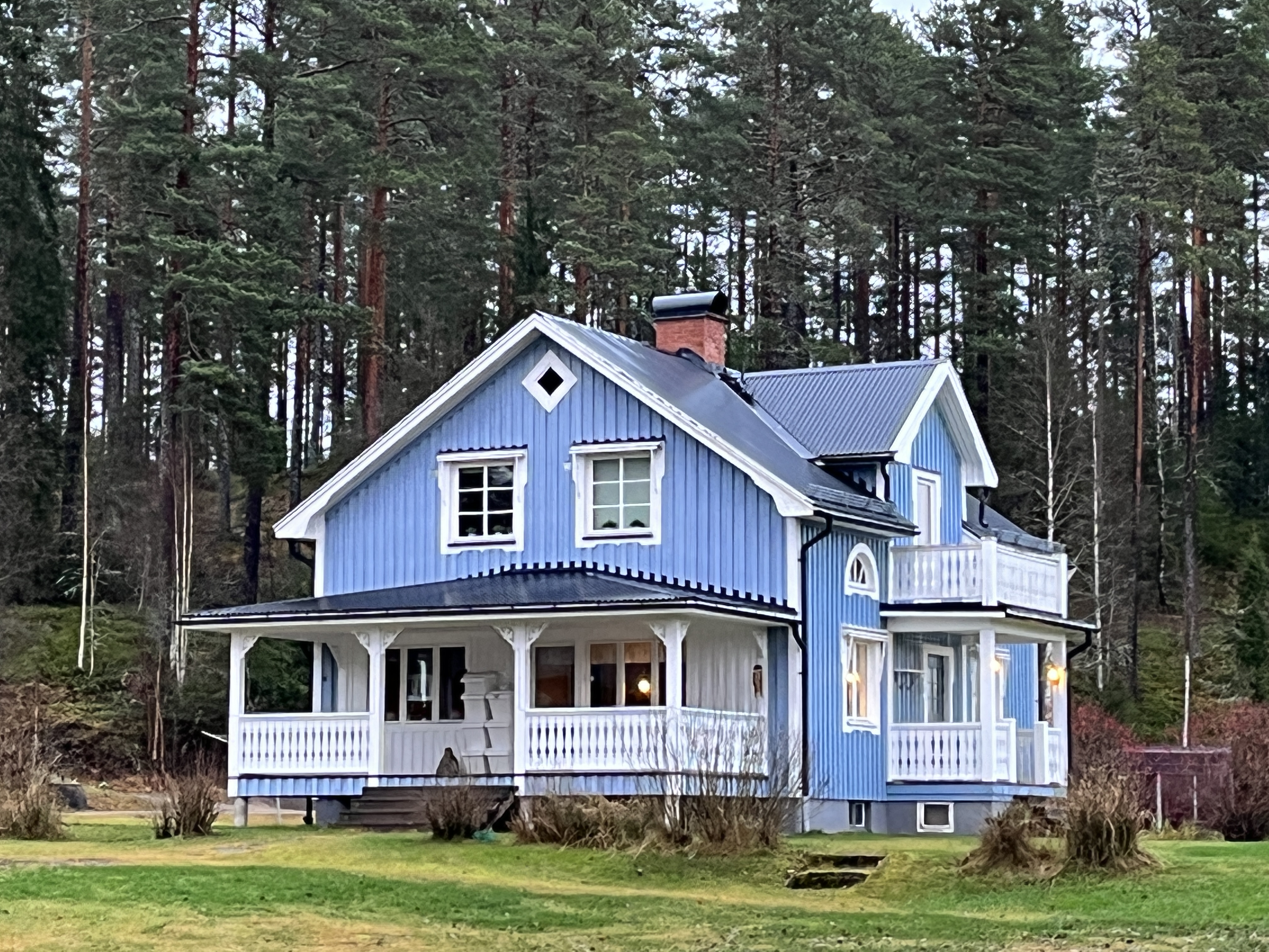 Blått trähus på Mörbacka Gård omringad av grönska