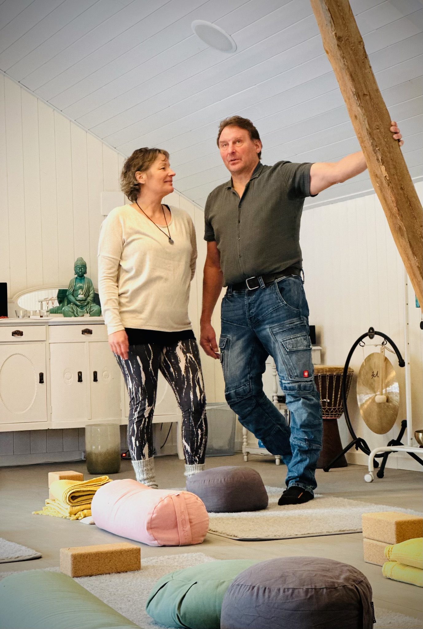 Camilla och Martin från Mörbacka Gård står i deras lokal omringad av yogamattor och kuddar