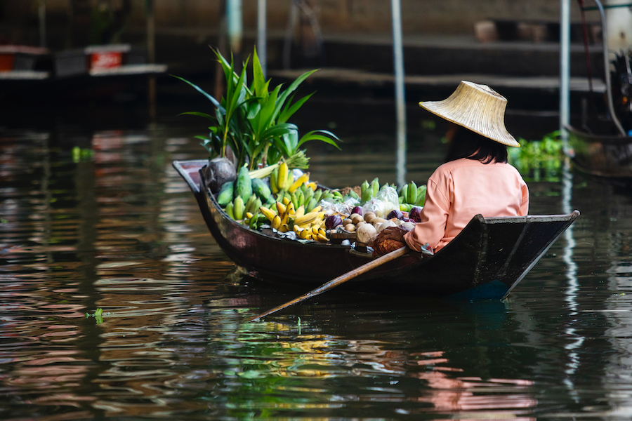 Exotic Fruits uk a woman in a boat filled with fresh exotic fruits, showcasing the vibrant selection at My Exotic Fruit