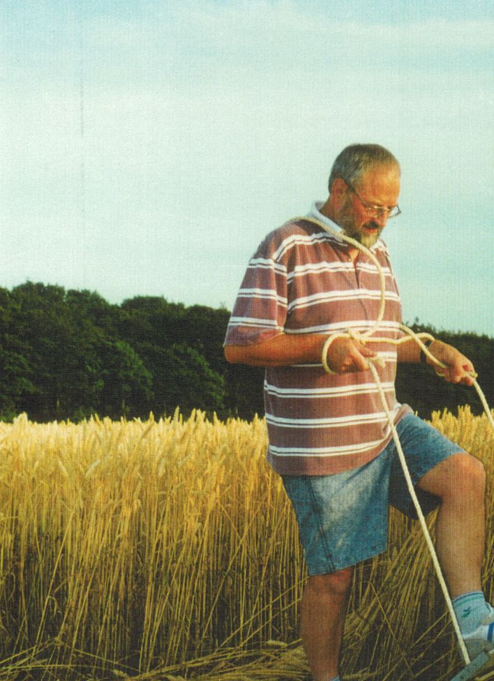 Vi tog det traditionelle instrument i brug - et brædt på ca. 80 cms længde og med en stump reb fastgjort i hver ende. Med brædtet trædes kornstråene langsomt ned, og med rebet trækkes brædtet op igen. Man fortsætter processen fremad og rundt, indtil man har den ønskede størrelse på cirklen. Efter kort tids øvelse har man lært at håndtere brædt og reb, så arbejdet hurtigt skrider frem, og med lidt omhu lægges kornstråene pænt, fladt ned mod jorden. Denne enkle fremgangsmåde kan anvendes til mange og ret så komplekse mønstre. 
Foto: Ole Henningsen
