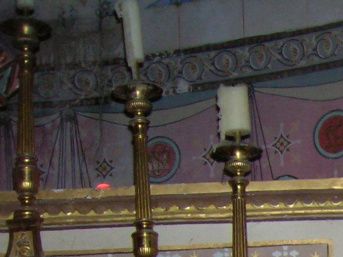 Parmi ses sponsors et acheteurs, l'abbé Saunière avait des conseillers francs-maçons qui lui ont inspiré certaines décorations de l'église aisément décodables: (UNE DÉCORATION, C'EST UNE RATION DE CODE) comptez les bougies, la disposition, la forme du cadre, ce chandelier fait d'un objet 4 codes. Photo Pierre-Henri Barnezet, 28/8/2005.