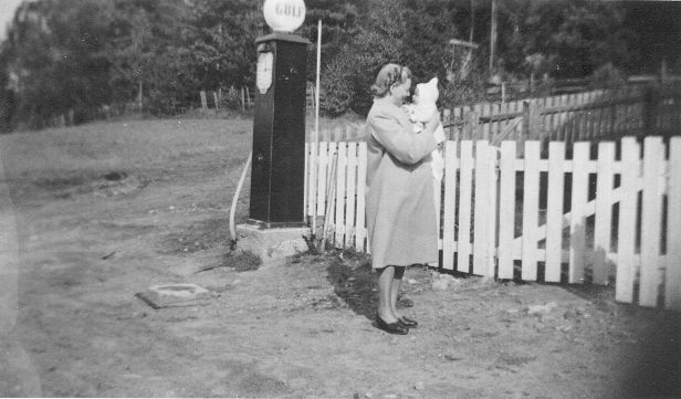 Helma Hansen med sønnen Bjørn på armen.
Her ser vi at Setskog Samvirkelag forhandlet Gulf bensin.
Bakenfor ser vi veien opp til den gamle idrettsbanen på Blakstad.