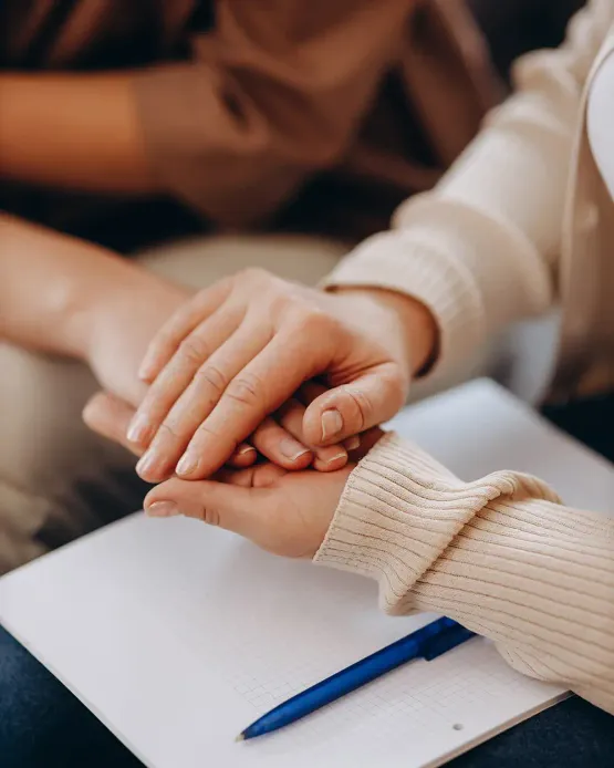Ein süßes Mädchen bei einem Termin beim Psychologen. Psychologin, die die Hände ihrer Patientin hält. Familienprobleme, Teena