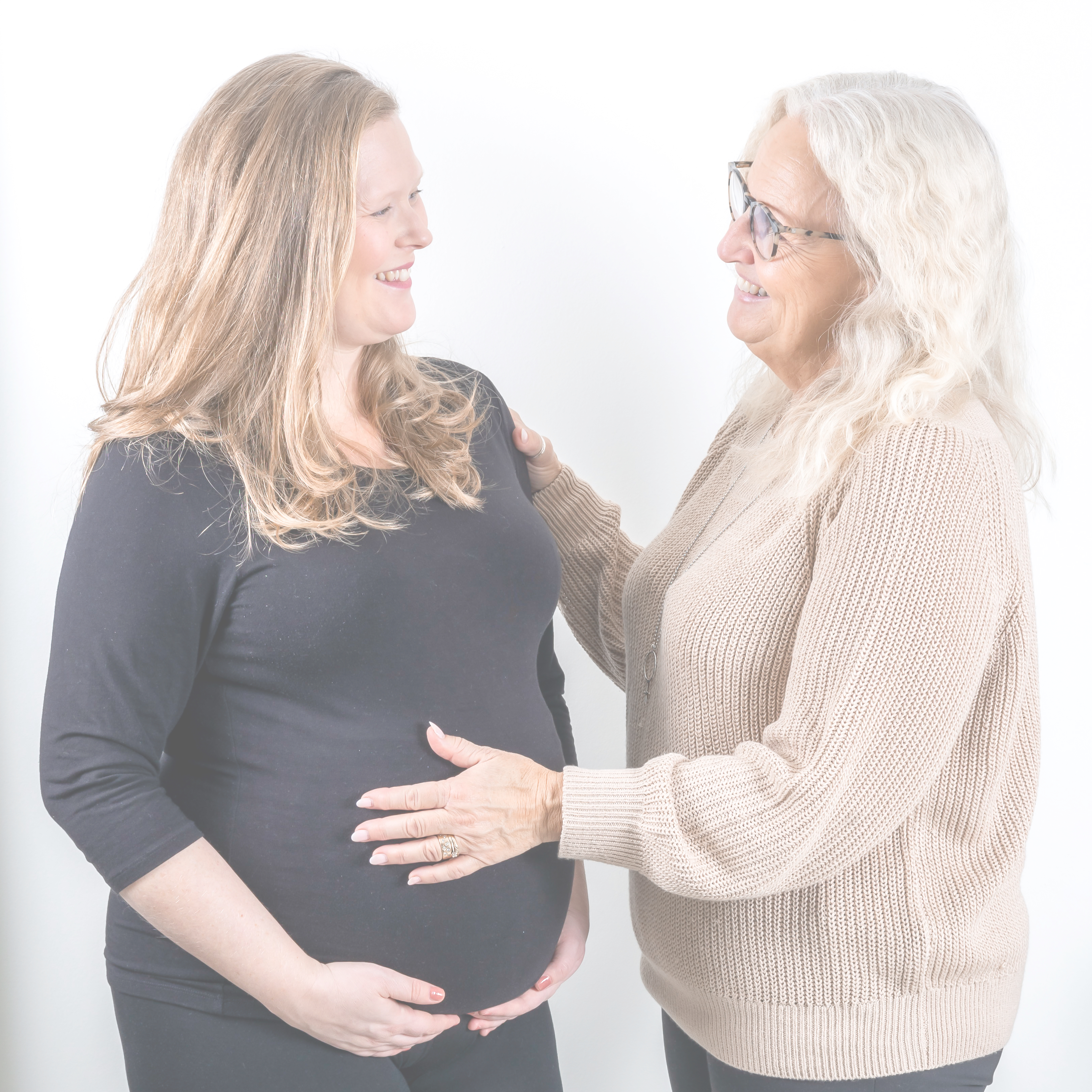 Leende doula håller hand på gravidmage..
