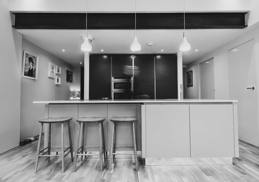 Black and white photo of a kitchen with island and bar stools
