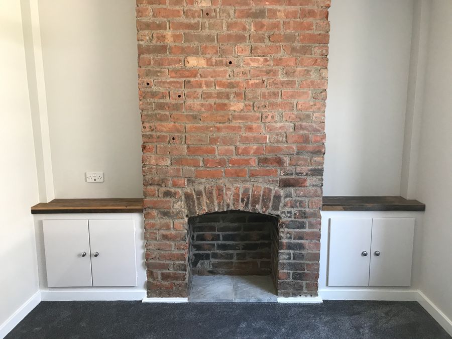 Exposed brick chimney breast with fitted alcove cupboards