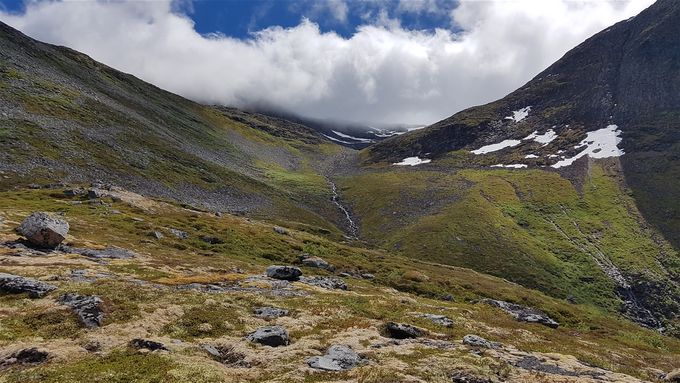 Veien opp etter skoggrensa er passert. Veien går til venstre ett godt stykke unna elva, men en ender opp i skaret midt på bildet (tåke denne dagen bildet ble tatt). Ryggen til topp 1222 m.o.h er til høyre