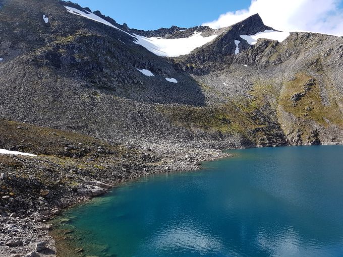 Her er veien mot Gullmorhornet på vestsiden av vannet. En må sikte seg omtrent mot det laveste punktet under den store breen. Her renner det ned en elv. Det er krevende å gå i ura.